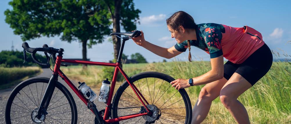 Eine Rennradfahrerin stellt die Neigung des Sattels ein.
