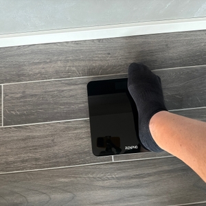 Ein großer Fuß steht zum Teil auf der Renpho BG260R.