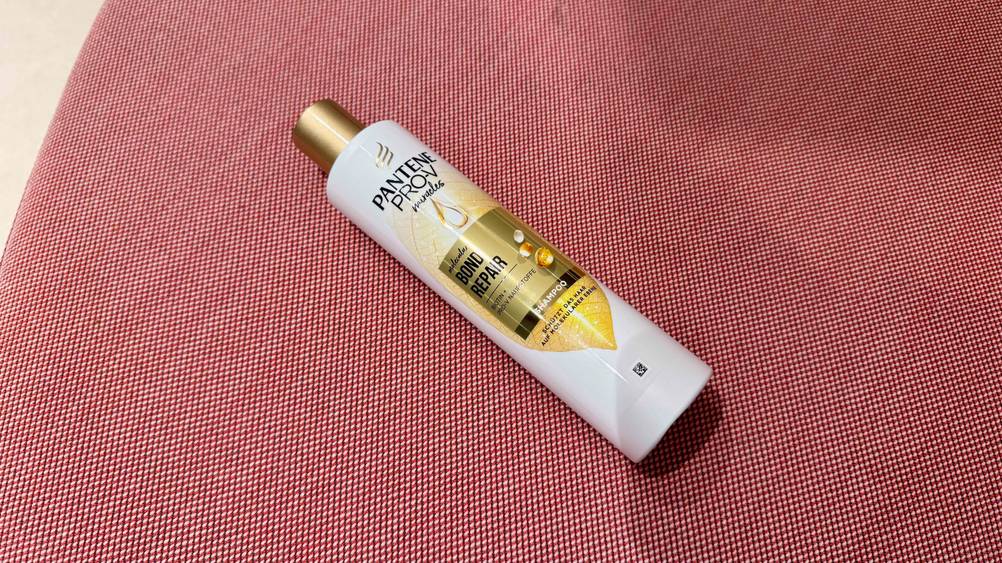 Eine Flasche des getesteten Repair Shampoos auf einem roten Teppich von oben.
