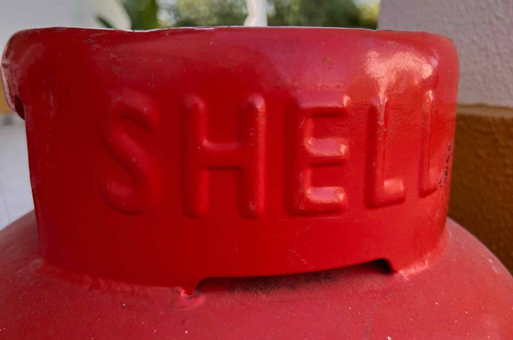Detailansicht einer roten, getesteten Propangasflasche inklusive Markenname von Shell im Außenbereich.