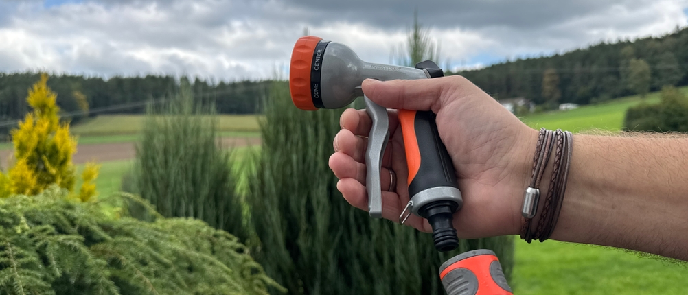 Eine Hand steckt die Restmo-Gartenbrause an einen Schlauch