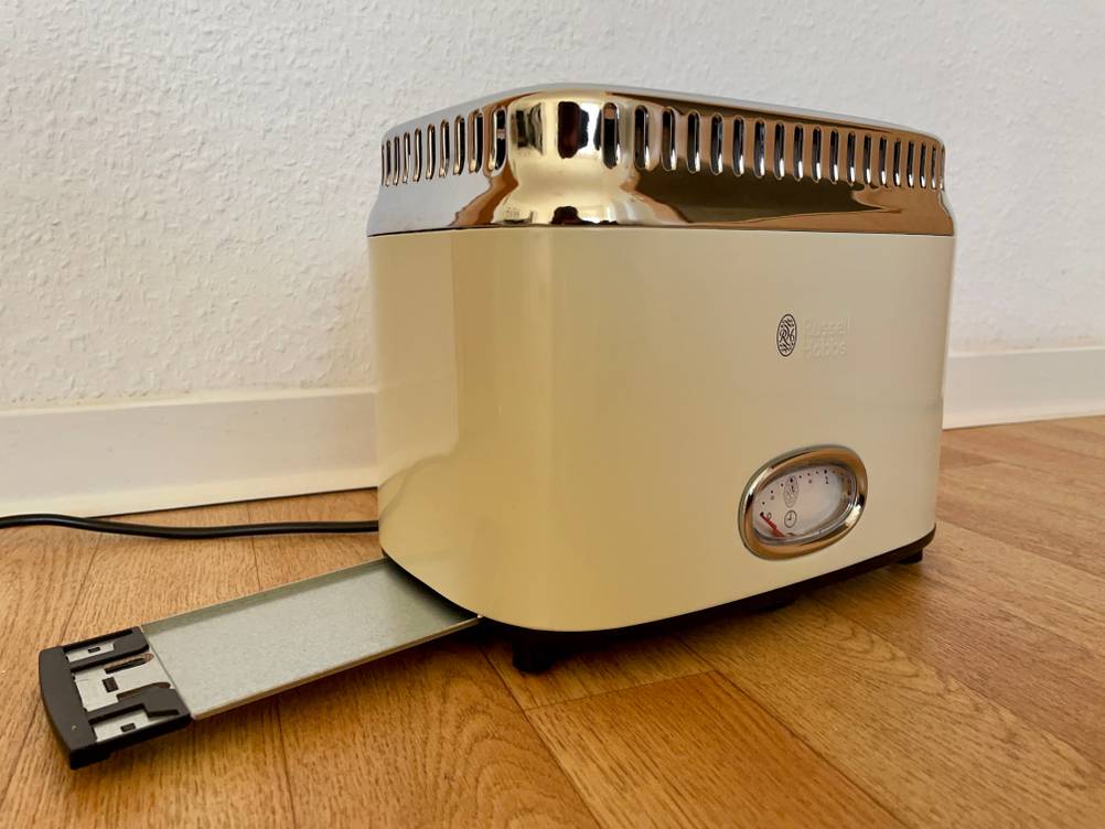 Retro-Toaster-Test: Ein Gerät mit ausgefahrener Krümelschublade auf einem Holzboden.