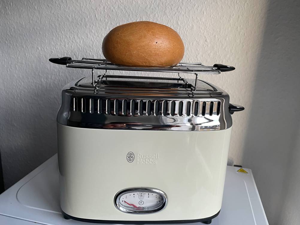 Retro-Toaster getestet: Ein Gerät mit mit Brötchenaufsatz und Brötchen von vorne vor einer hellen Wand.