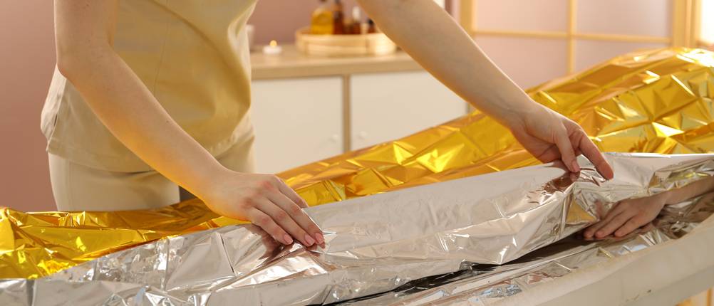 Rettungsdecke getestet: Eine Frau legt eine Rettungsdecke über eine liegende Person.