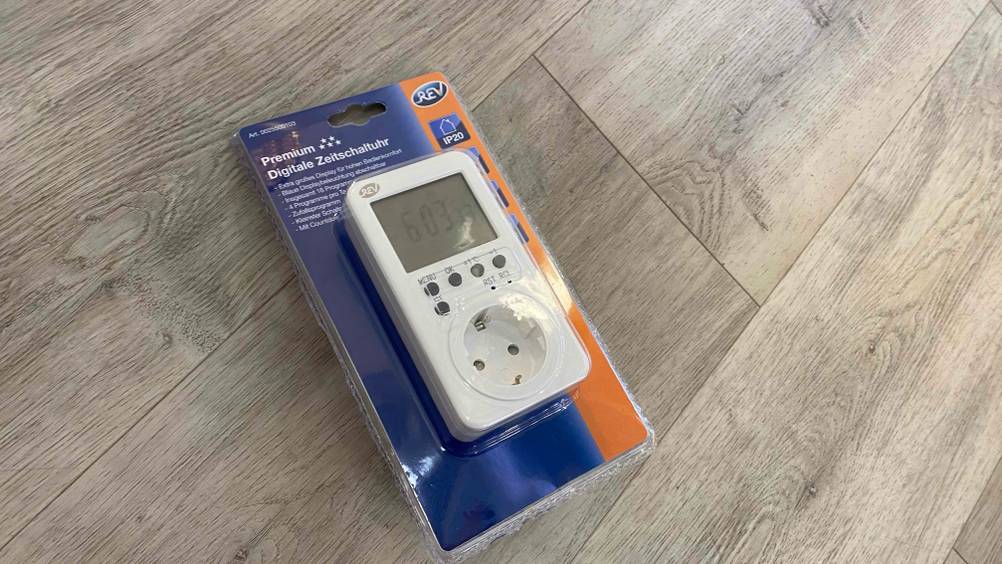 Getestet: Ein originalverpackte digitale Zeitschaltuhr liegt auf einem Holzfußboden.