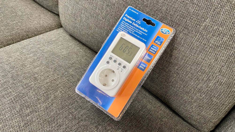 Digitale Zeitschaltuhr getestet: Eine verpacktes Digitale Zeitschaltuhr lehnt an einem grauen Polster.