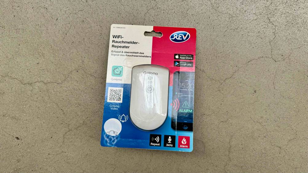 Getesteter Smart-Home-Rauchmelder befindet sich auf einem grauen Untergrund.