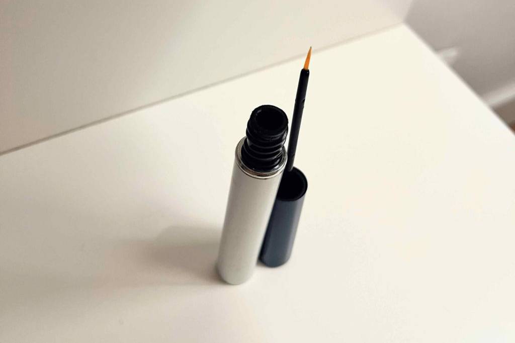 Im Test: geöffneter Behälter Revitalash Wimpernserum in einem weißen Regal, von oben betrachtet.