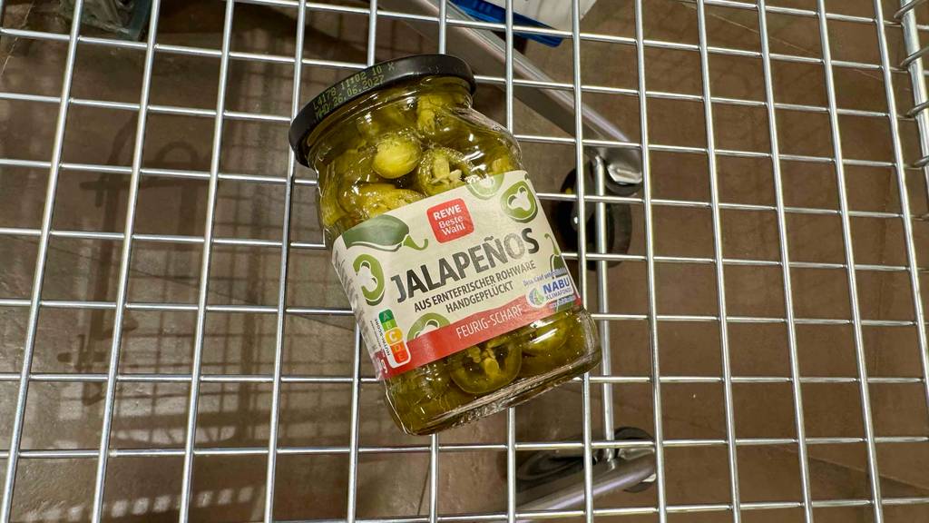 Ein Glas Jalapenos steht zum testen liegt in einem Einkaufswagen.