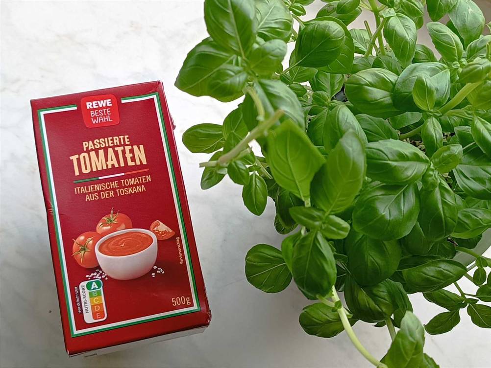 Passierte Tomaten neben Basilikum