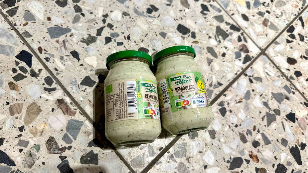 Im Test: Zwei Gläser Remoulade liegen nebeneinander auf einem Fliesenboden, eines davon auf die Seite gerollt.