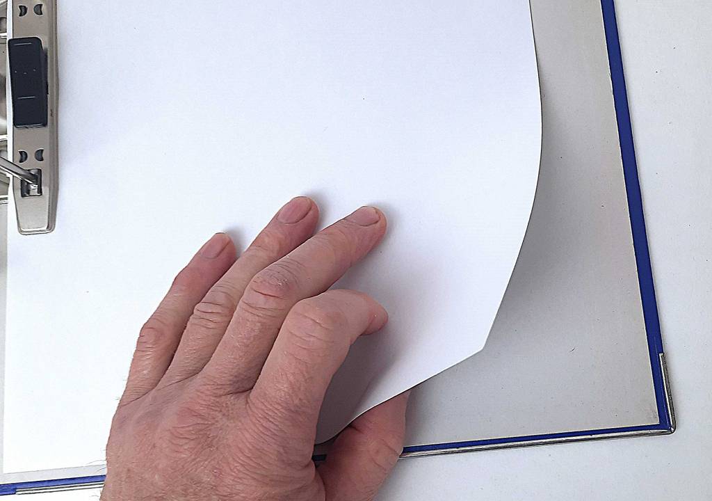 Eine Hand blättert ein Blatt in einem getesteten Aktenordner um.