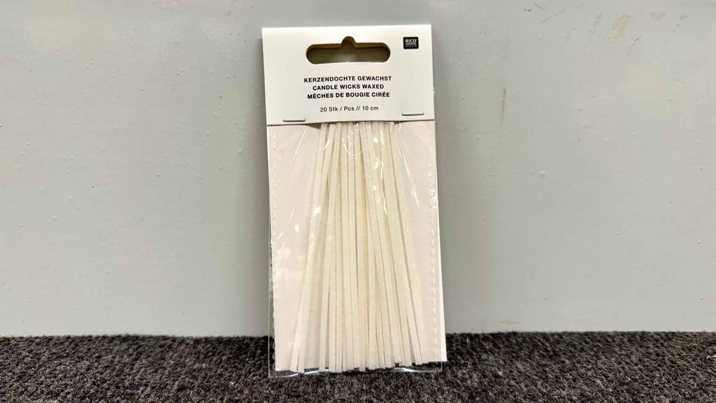 In einer 20-Stück-Packung lehnen die getesteten Kerzendochte an einer weißen Wand.