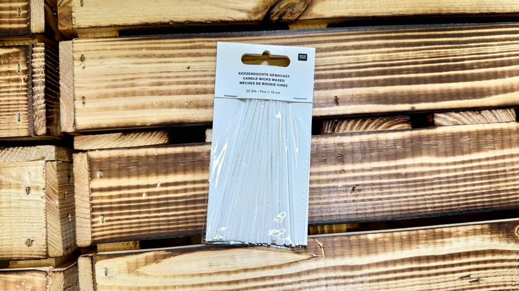 Im Test: Kerzendochte in der 20-Stück-Packung befinden sich auf einem Holzuntergrund.