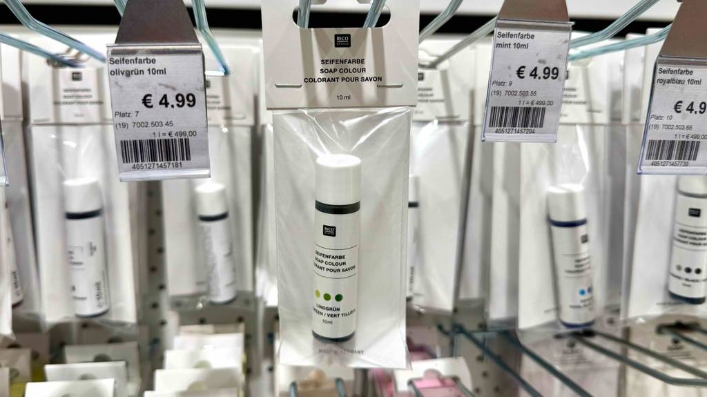 Verschiedenfarbige getestete Seifenfarben in 15-mg-Kunststoffflaschen hängen an einem Verkaufsregal.