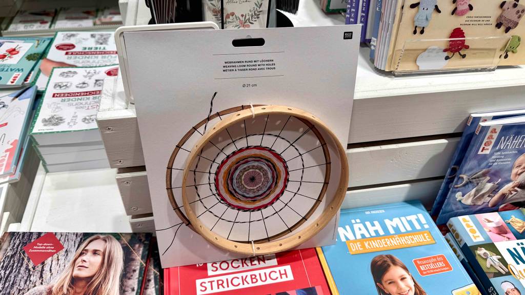 Getestet: Der Webrahmen in runder Ausführung steht inklusive Kartonage auf mehreren Büchern mit Handarbeitsanleitungen.