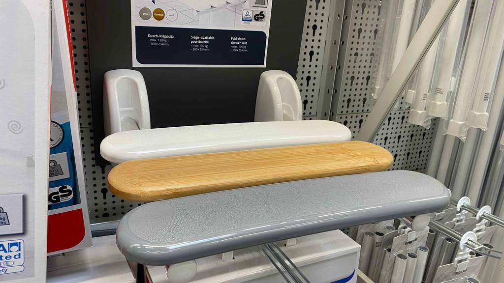 Duschklappsitz-Test: ein dreifarbiges Modell (weiß-grau-holz) ist in einem Verkaufsbereich ausgestellt.