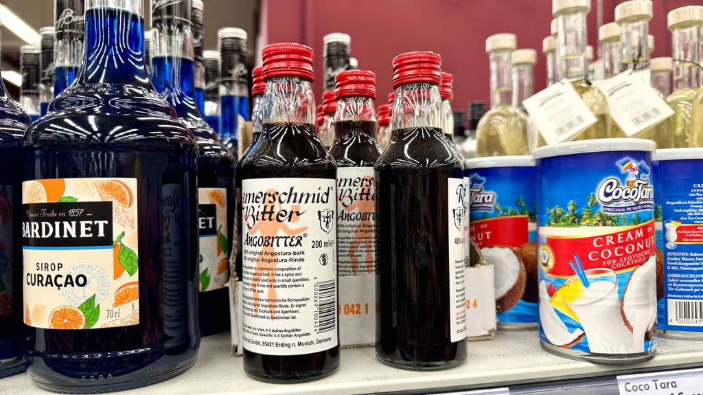 Bitters im Test: Mehrere Flaschen stehen zwischen anderen Produkten in einem Regal.