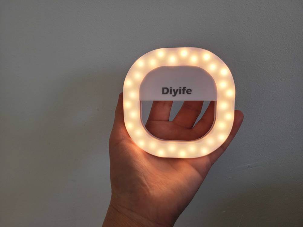 Eine Hand hält ein getestetes Ringlicht für das Handy mit Warmlicht. 