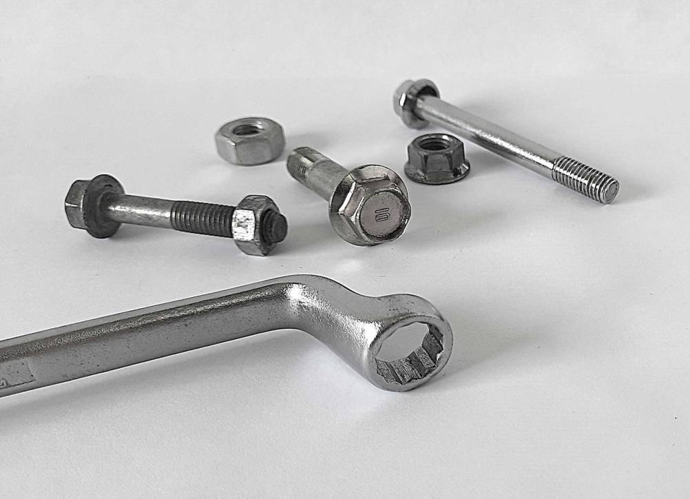 Der getestete Ringschlüssel mit mehreren Schrauben und Muttern auf einer hellen Fläche.
