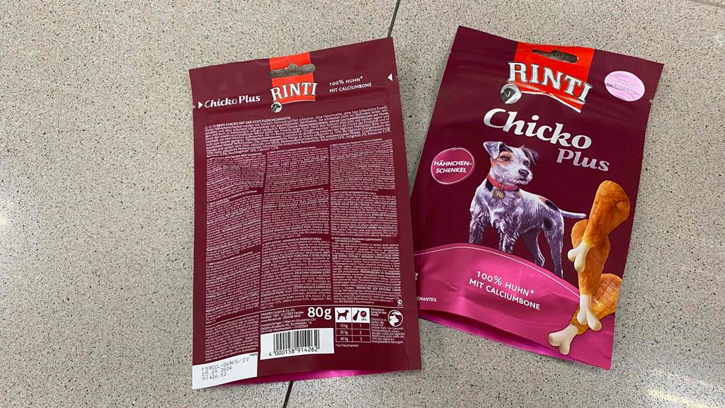 Zwei Packungen mit Vorder und Rück-Ansicht von Rinti-Hundefutter im Test liegen auf dem Boden.