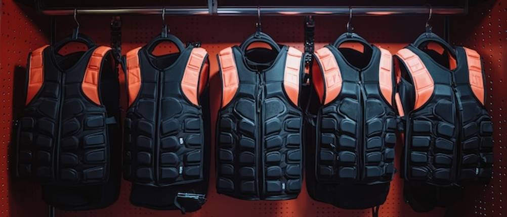 Rippenschutz getestet: In einer Garderobe hängen mehrer schwarze Rippenschutze mit einer Armblende in Orange.