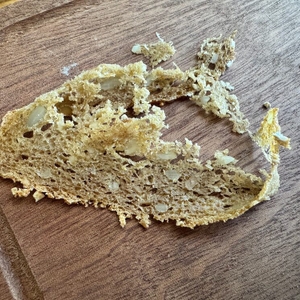 Eine zerfallene Scheibe Vollkornbrot liegt auf einem Holzbrett