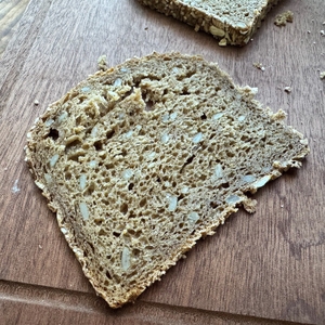 Eine dünne Scheibe Vollkornbrot liegt auf einem Holzbrett