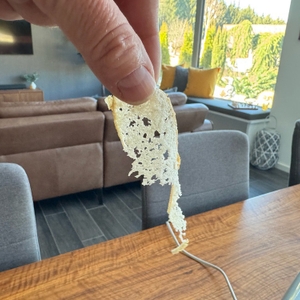 Eine Hand hält eine hauchdünne, halb zerfallene Scheibe Weißbrot fest