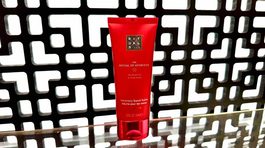 Rituals-Handcreme-Test: Eine rote Tube steht vor einer schwarz-weiß gemusterten Wand.