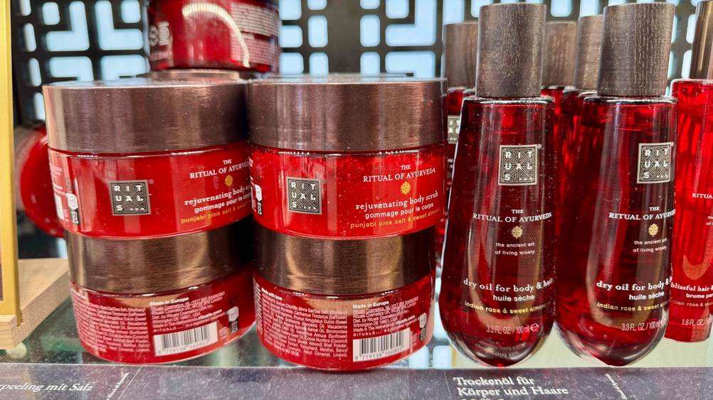 Mehrere Dosen des Rituals-Peeling im Test auf einem Verkaufsregal neben anderen Produkten.