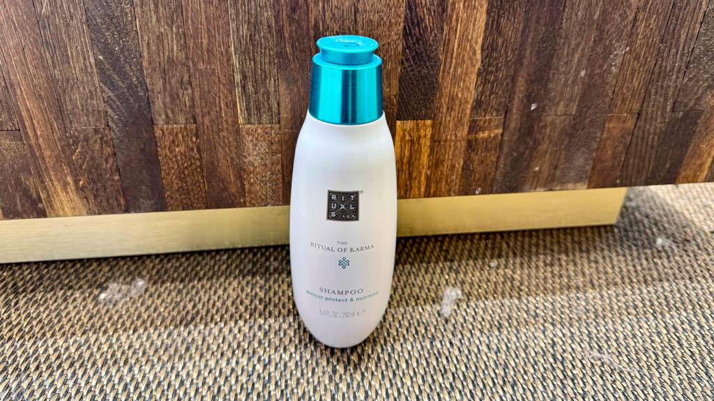 Eine Flasche getestetes Rituals-Shampoo steht vor einer Holzwand.
