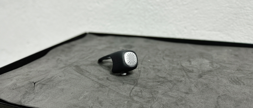 Die Rockbros-Fahrradklingel liegt auf einer schwarzen Oberfläche. Die Vorderseite mit Lautsprechergitter ist gut erkennbar.