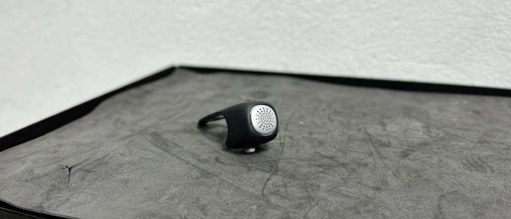 Die Rockbros-Fahrradklingel liegt auf einer schwarzen Oberfläche. Die Vorderseite mit Lautsprechergitter ist gut erkennbar.