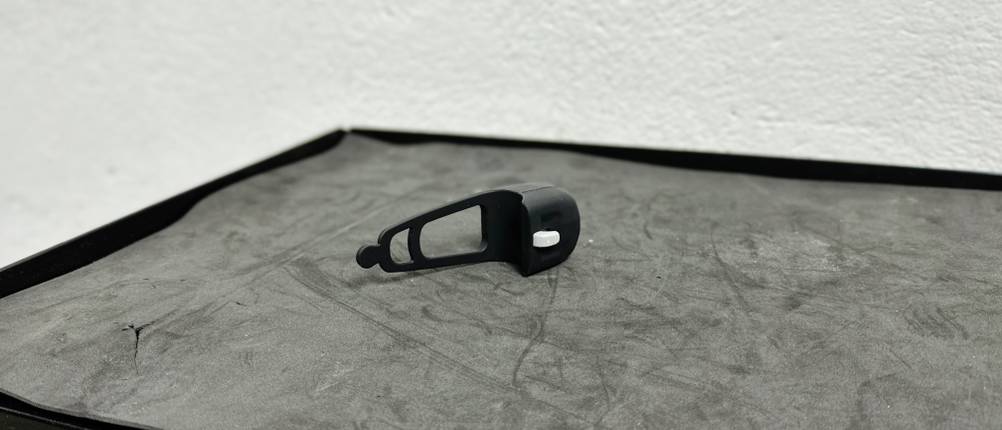 Seitenansicht der Rockbros-Fahrradklingel auf einer schwarzen Oberfläche. Die seitlichen Bedienelemente sind gut sichtbar.