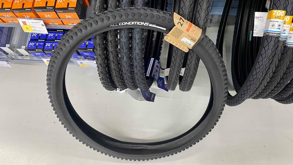 Im Test: ein MTB-Reifen mit 27,5 Zoll (0,7 m) von vorn steht vor verschiedenen Reifen, die sich in einem Verkaufsregal befinden.