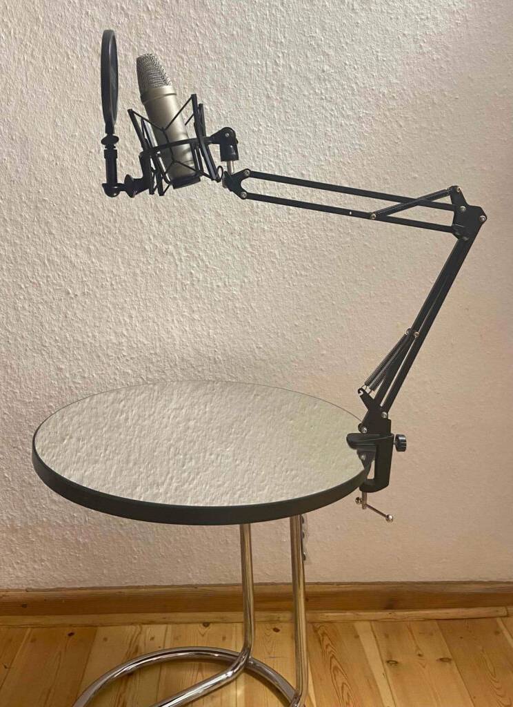 Mikrofonarm im Test: ein schwarzer Mikrofonarm ist mittels Tischklemme an einem Glastisch befestigt.