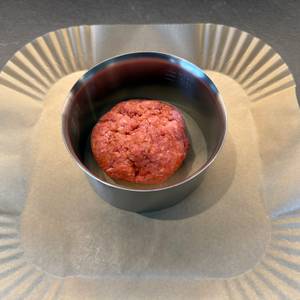 Ein Fleischbällchen liegt in der Rösle-Burgerpresse PRO