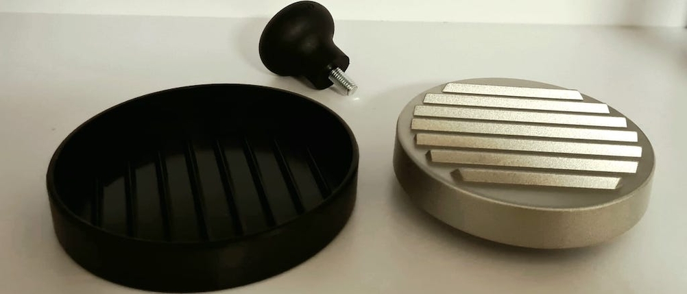 Drei Einzelteile einer Burgerpresse aus Edelstahl