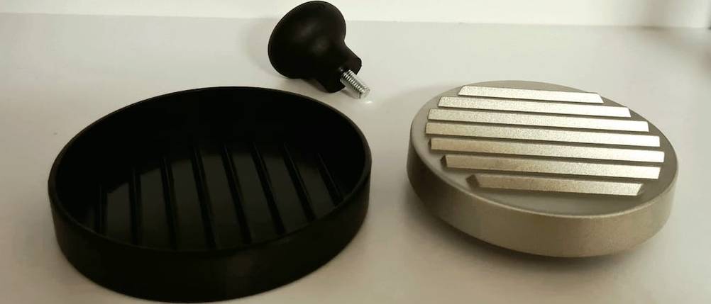 Drei Einzelteile einer Burgerpresse aus Edelstahl