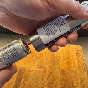 Eine Hand befestigt das Butangas am Rösle-Flambierbrenner