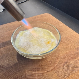 Zucker auf Pudding wird mit dem Rösle-Flambierbrenner flambiert