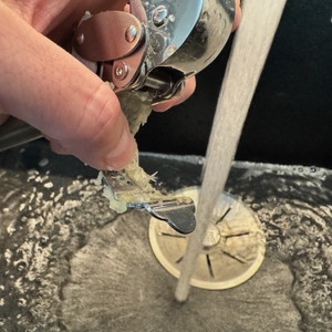 Die benutzte Knoblauchpresse wird unter einen Wasserstrahl zur Reinigung gehalten.