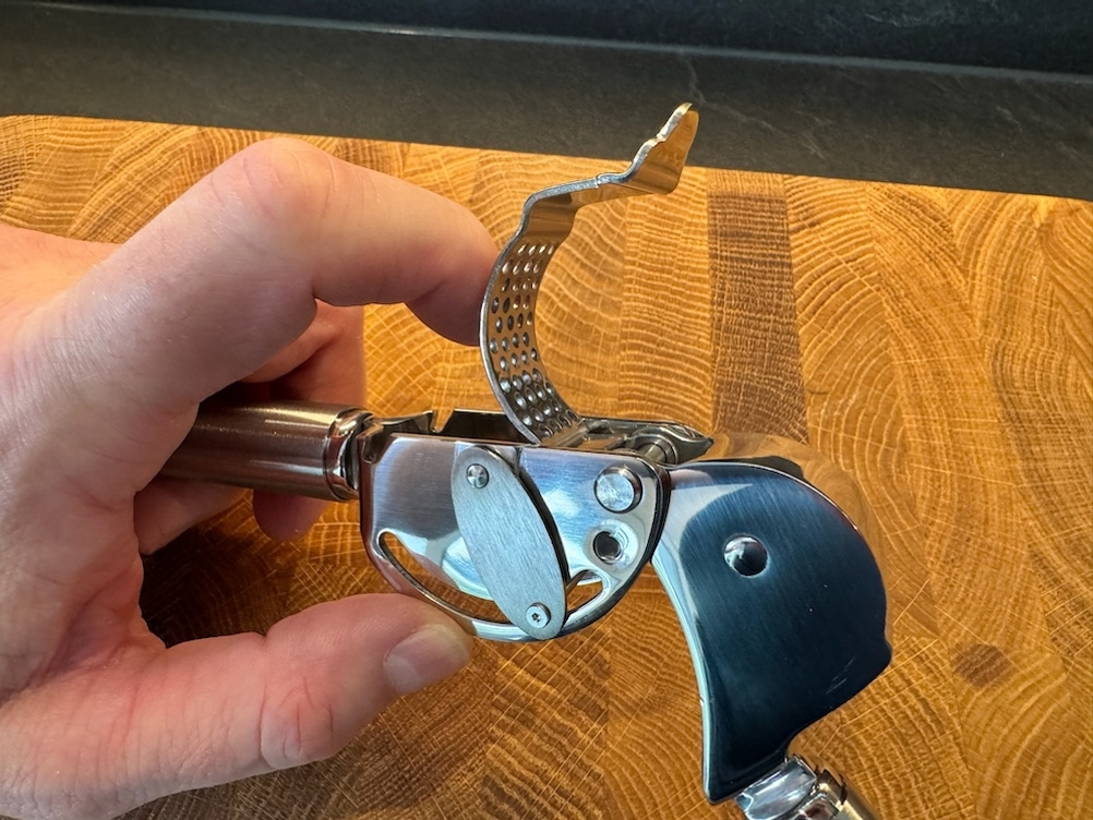Ein Finger hebt den Abstreifer der Rösle Knoblauchpresse an.
