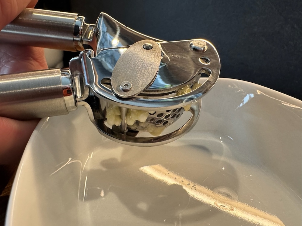 Pressvorgang bei der Rösle Knoblauchpresse über einer Schale.