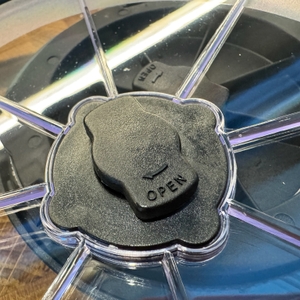 Open-Zeichen eines Deckels bei der Rösle Salatschleuder mit Glasdeckel