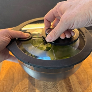 Hand kurbelt mit der Rösle Salatschleuder mit Glasdeckel