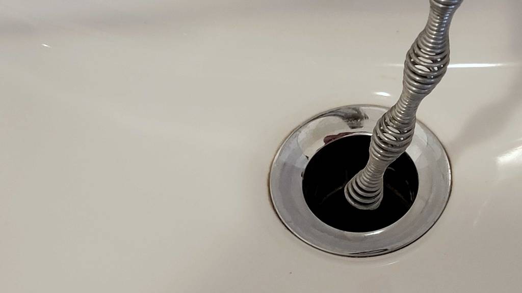 Eine getestete Rohrreinigungsspirale steckt in einem Abfluss.