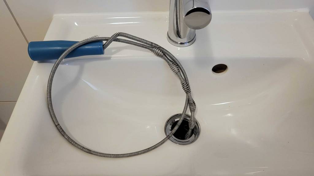 Rohrreinigungsspirale im Test: Eine Spirale liegt auf einem Waschbecken, zum Teil im Abfluss.