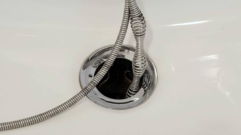 Rohrreinigungsspirale-Test: Detailansicht eines Teils einer Spirale, die in einen Abfluss eingeführt wird.